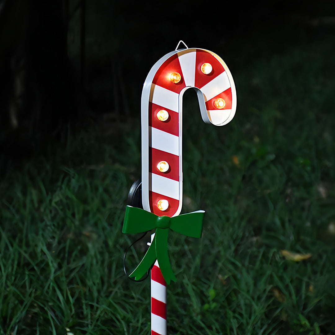 Illuminated Christmas tree ground stake for Christmas lights placed outdoors in snowy holiday scenery.