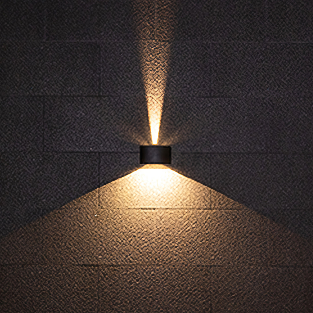 Outdoor up down wall light casting single focused downlight beam at night