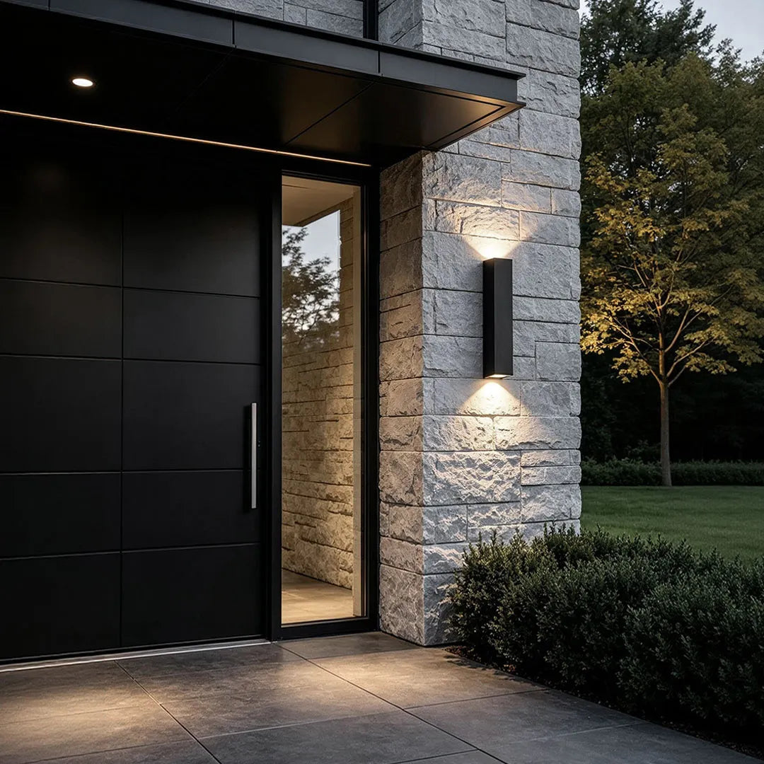 Outdoor up down wall lights illuminating a modern stone entryway