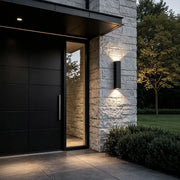 Outdoor up down wall lights illuminating a modern stone entryway