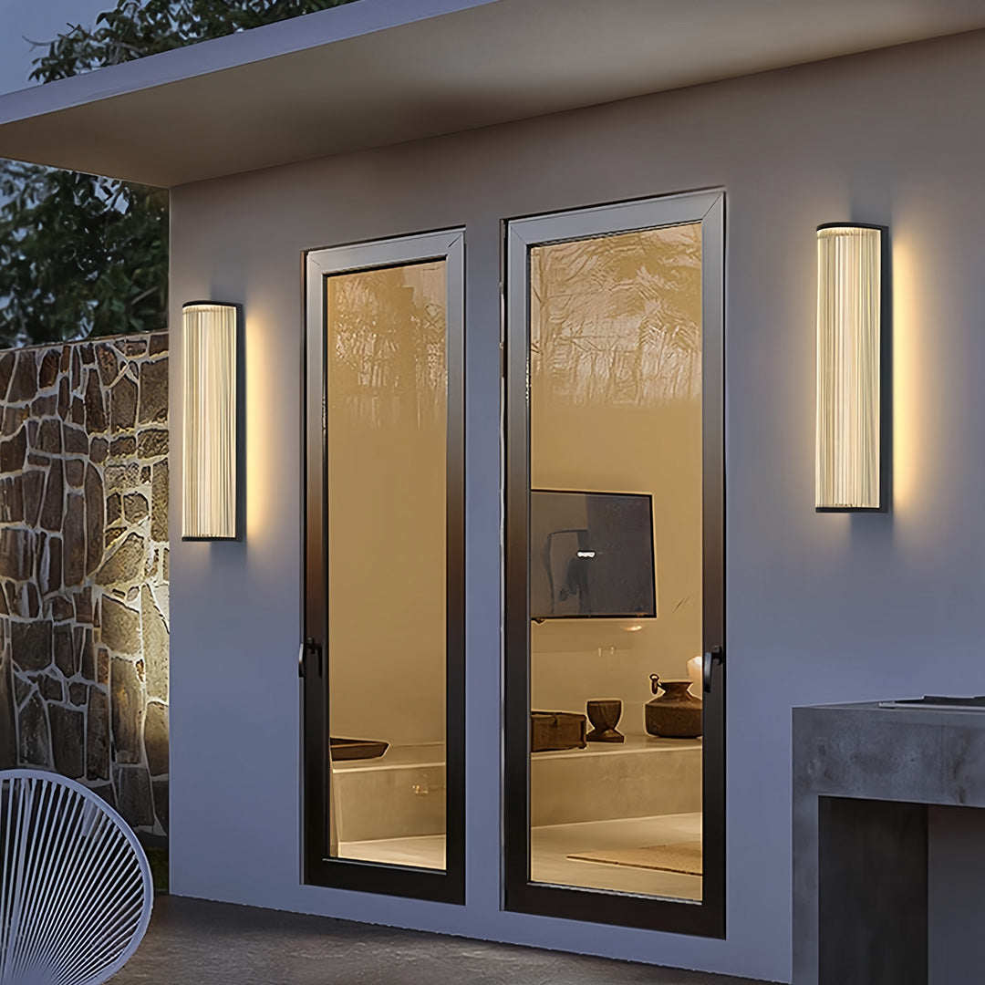 Outdoor vertical wall sconce lighting enhancing the architectural columns of a covered walkway at night.
