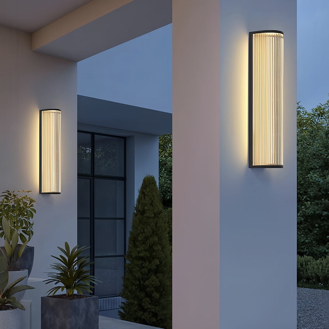 Outdoor vertical wall sconce lighting enhancing the entrance of a house with soft, upward glow.
