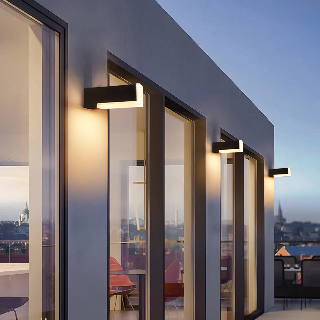 Outdoor wall lantern light fixtures illuminating a modern house facade with warm ambient glow.