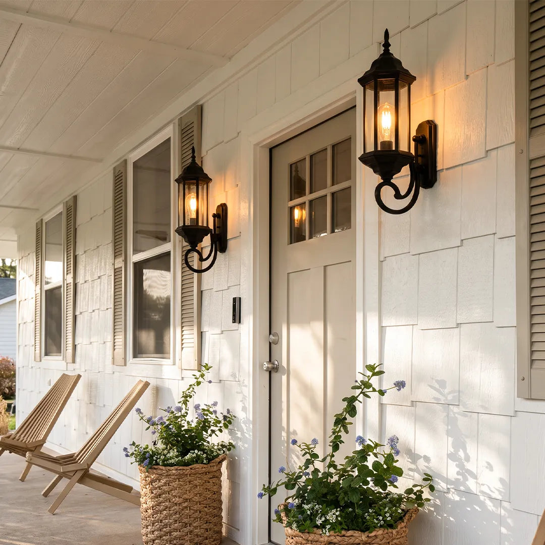 Outdoor wall lantern light mounted beside a white entry door on a covered porch with black metal finish.