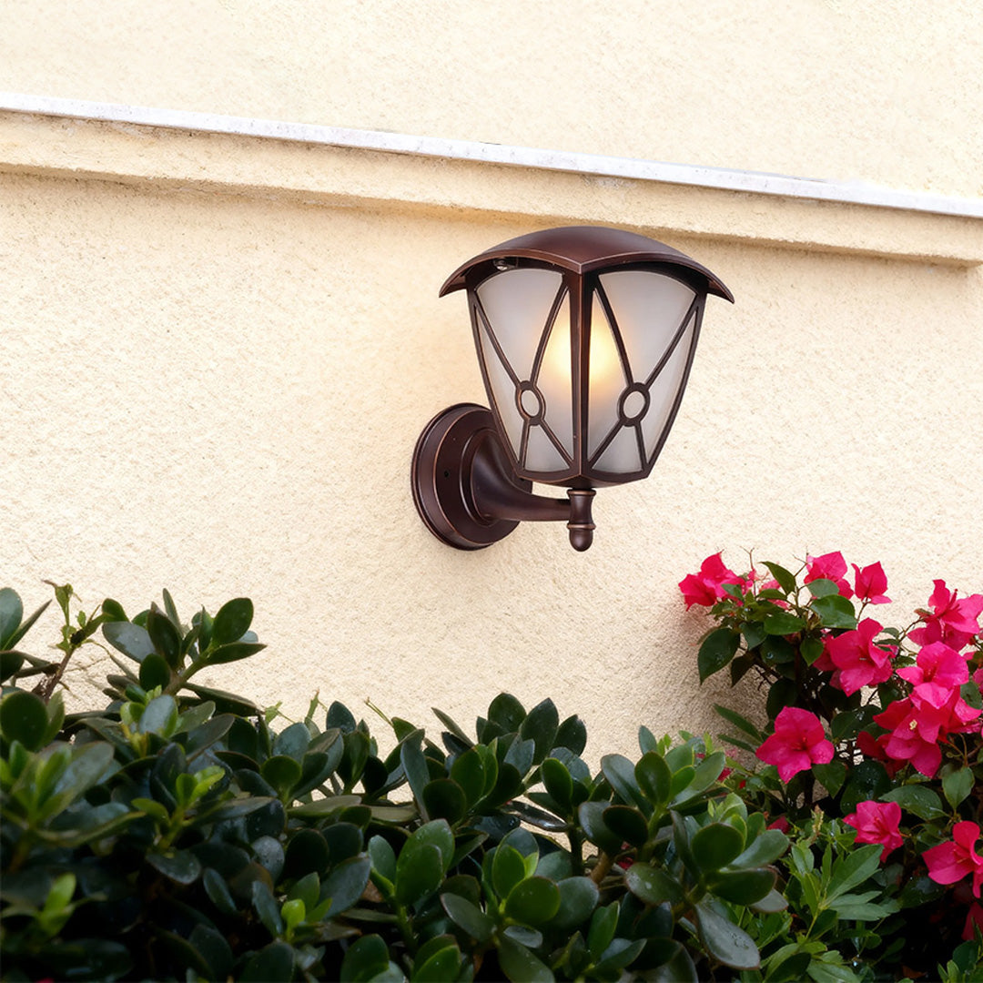 Outdoor wall light for house brightening cream-colored facade near pink flowering bougainvillea
