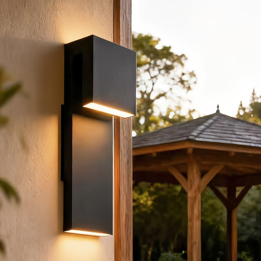 industrial outdoor wall light installed on exterior wall near patio area emitting warm light