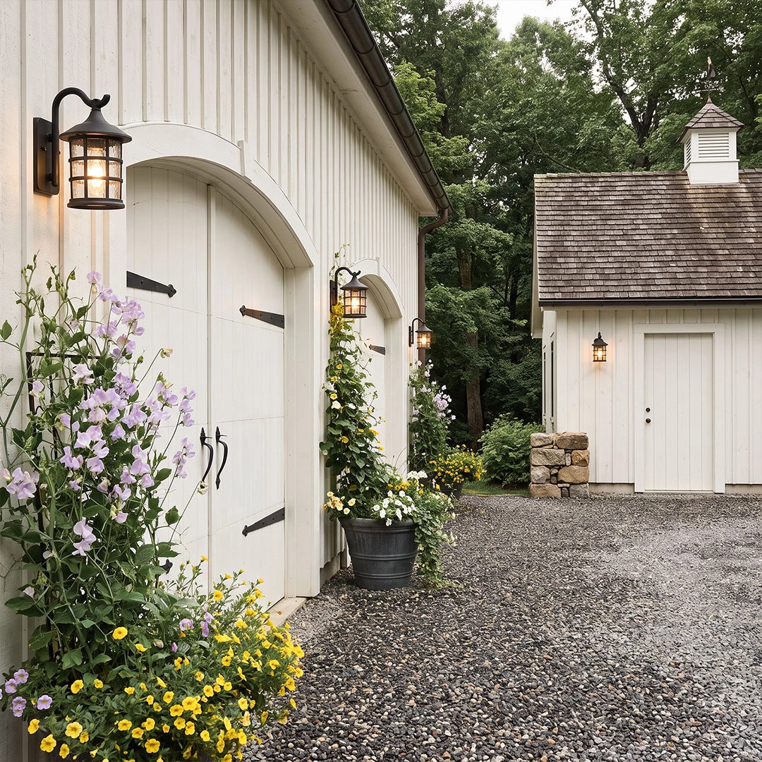 Outdoor wall light lantern installed beside a carriage house garage with a cottage-style exterior.