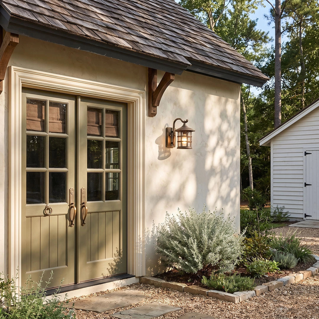 Outdoor wall light lantern beside double doors on a rustic outbuilding with warm exterior lighting.