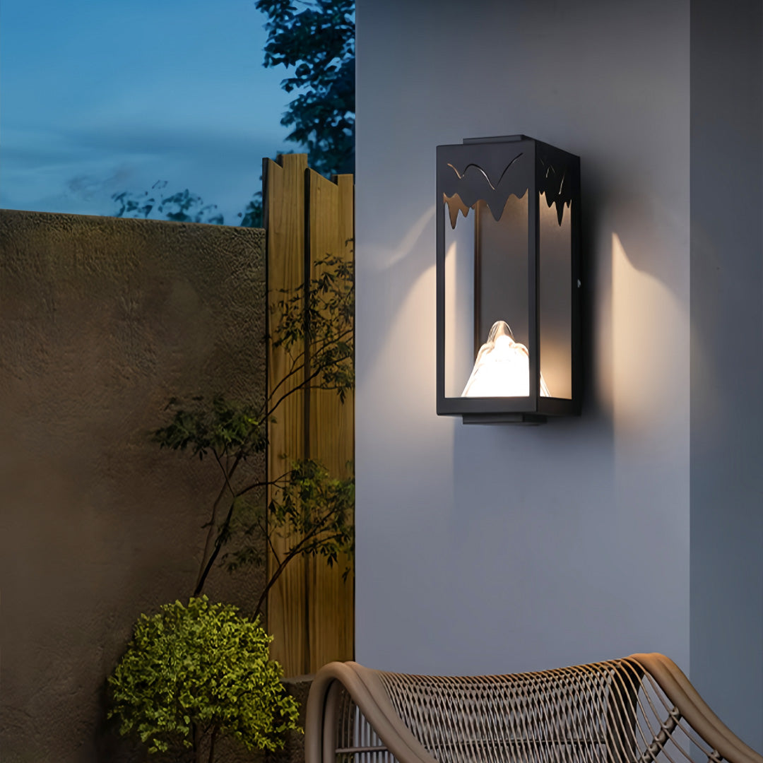 Outdoor wall lighting ideas providing accent lighting on textured wall beside outdoor seating area at dusk
