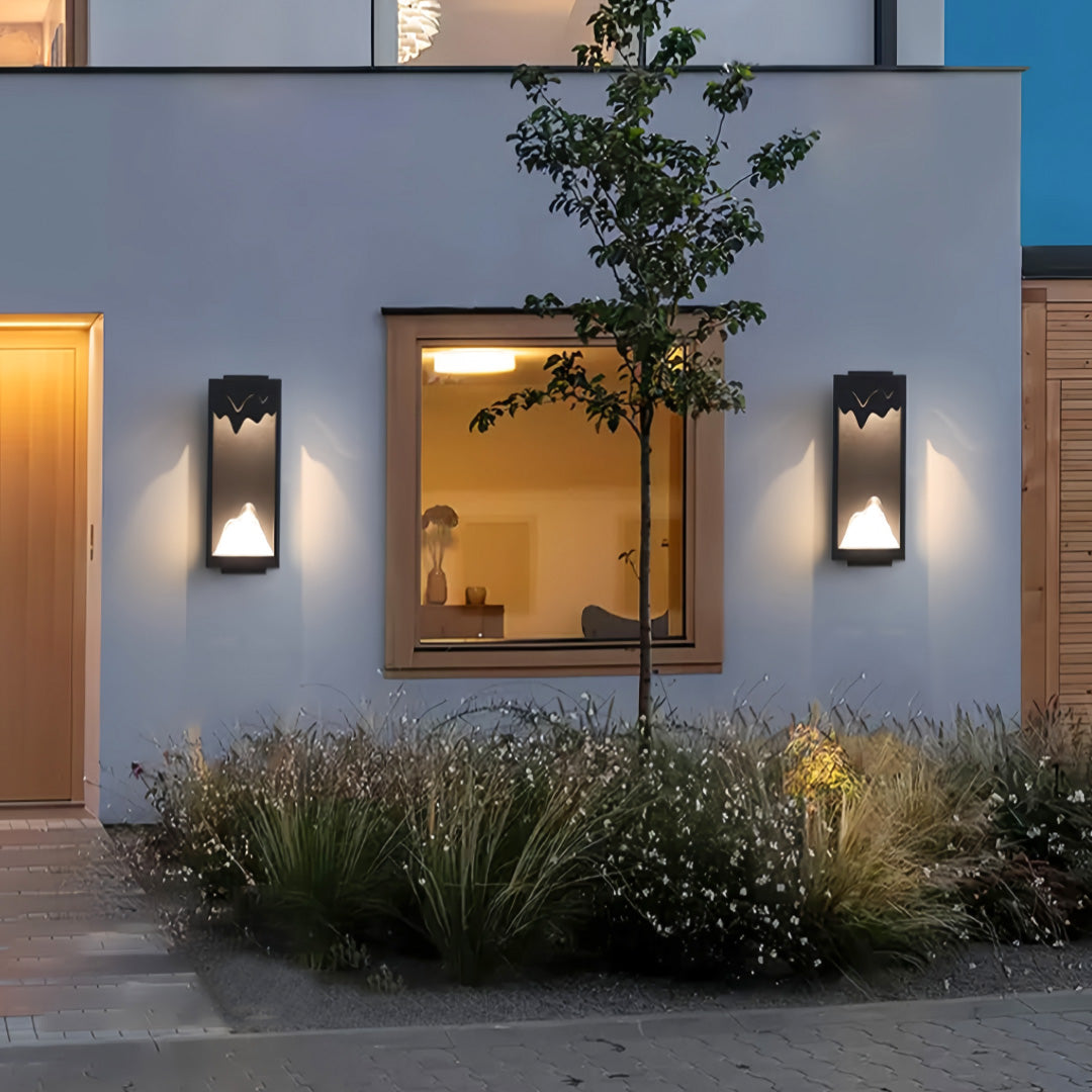 Outdoor wall lighting ideas illuminating blue-gray facade with decorative planters creating sophisticated evening ambiance