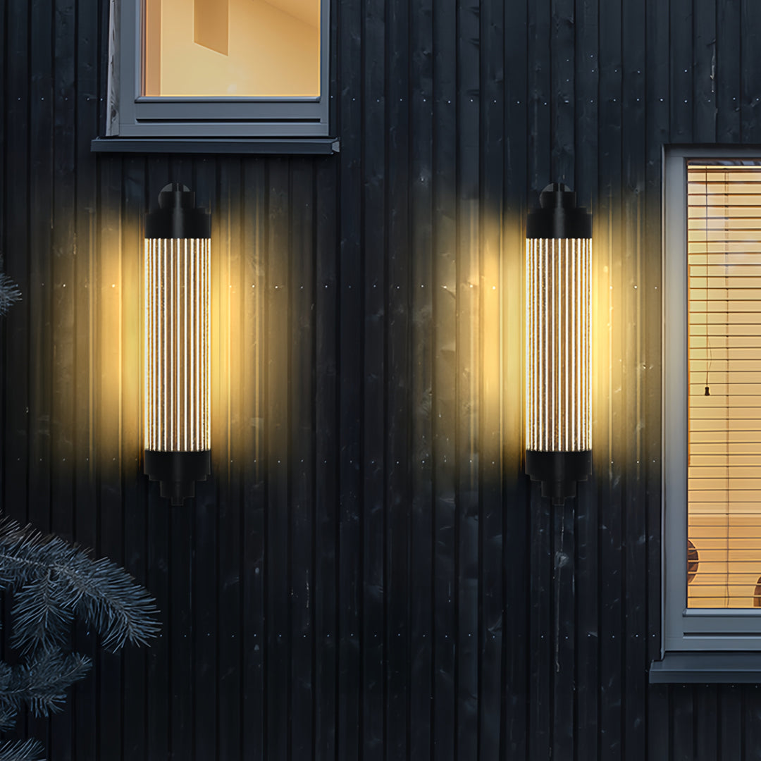 Vertical outdoor wall lighting LED sconces glowing warmly on a dark textured exterior facade at night.