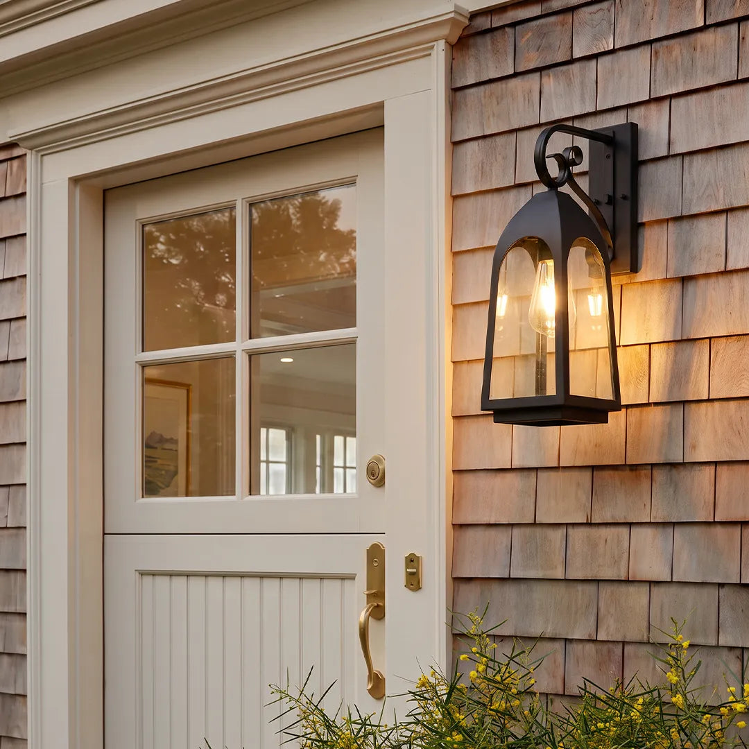 Outdoor wall mount lights on cedar shingle siding beside a white exterior door with glass panels.