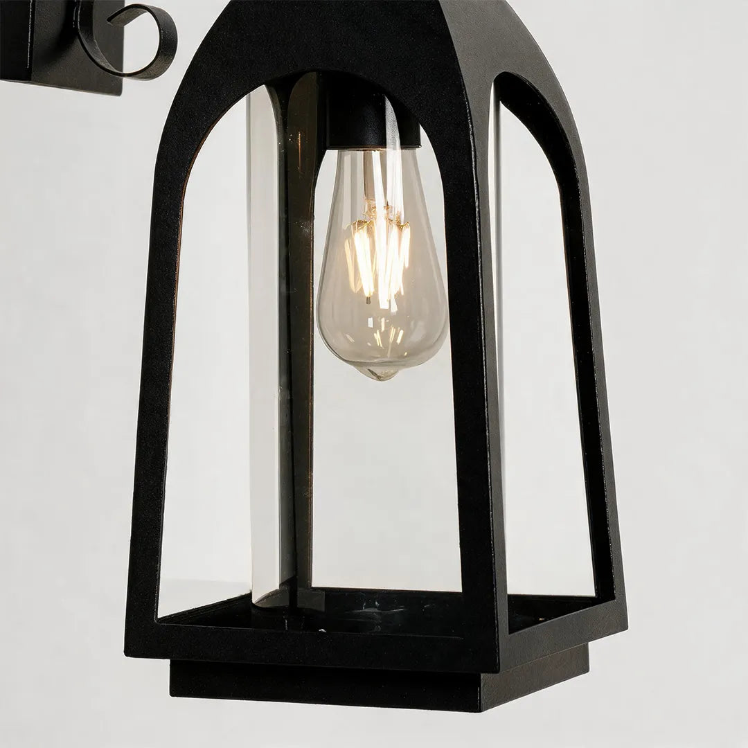 Outdoor wall mount lights product close-up showing a black lantern fixture with clear glass and exposed bulb.