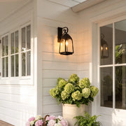 Outdoor wall mount lights beside a white entry door with hydrangea planters on a cottage-style porch.