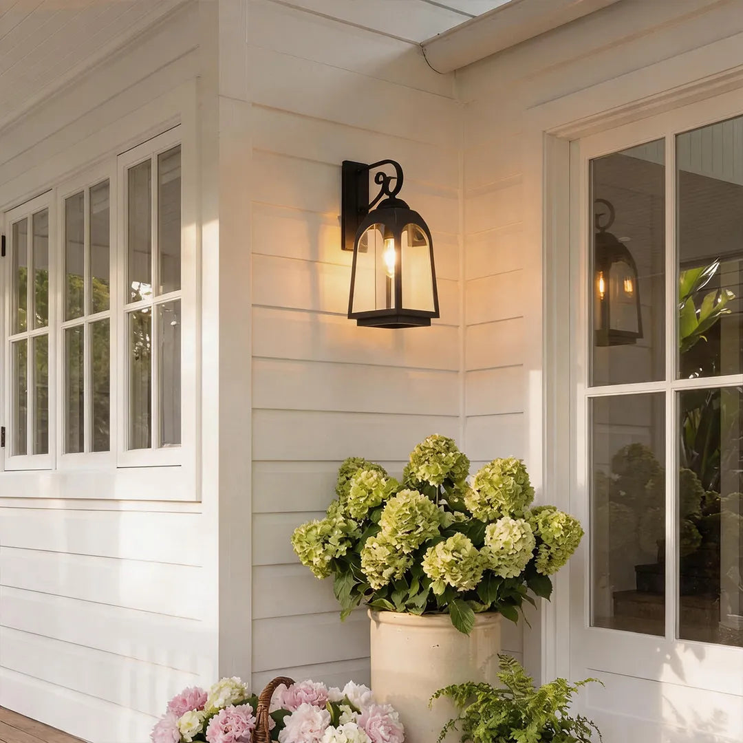Outdoor wall mount lights on white siding above hydrangeas and beside a window.