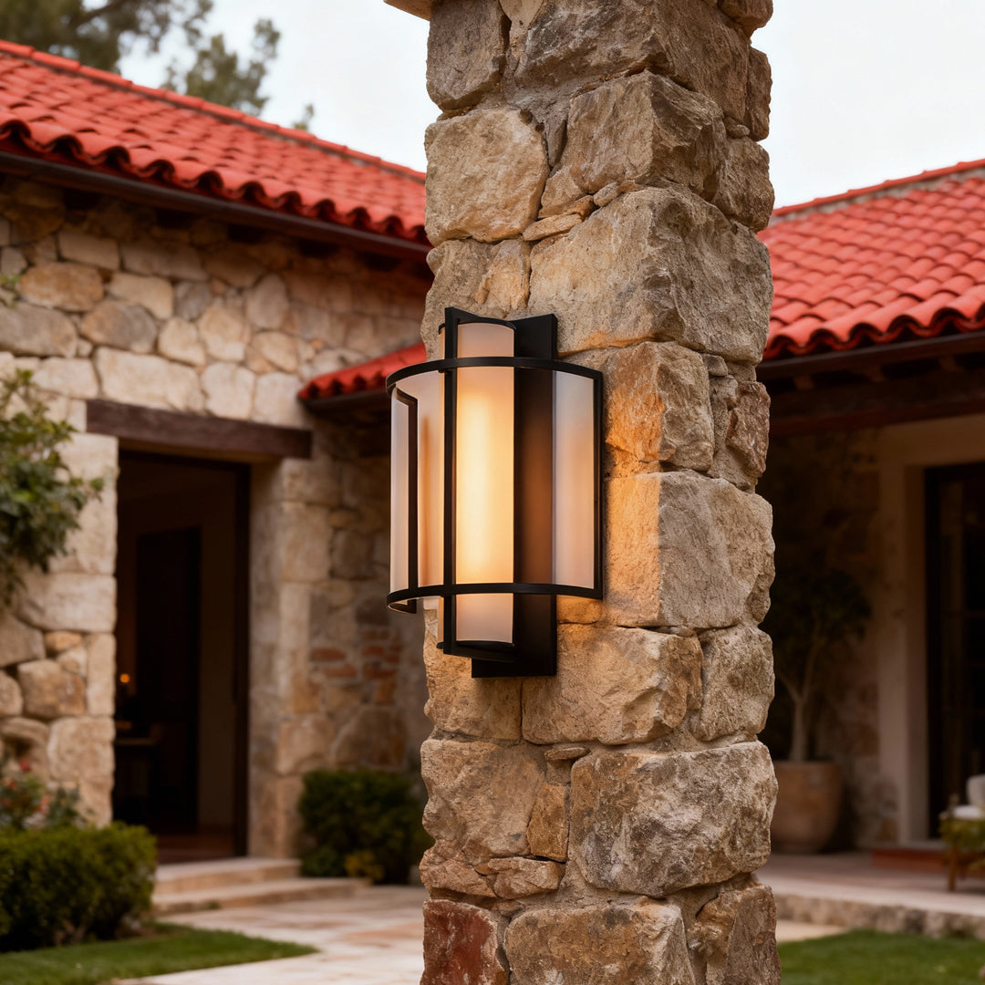 Rustic stone wall accented with elegant outdoor wall mounted lighting producing soft evening illumination.