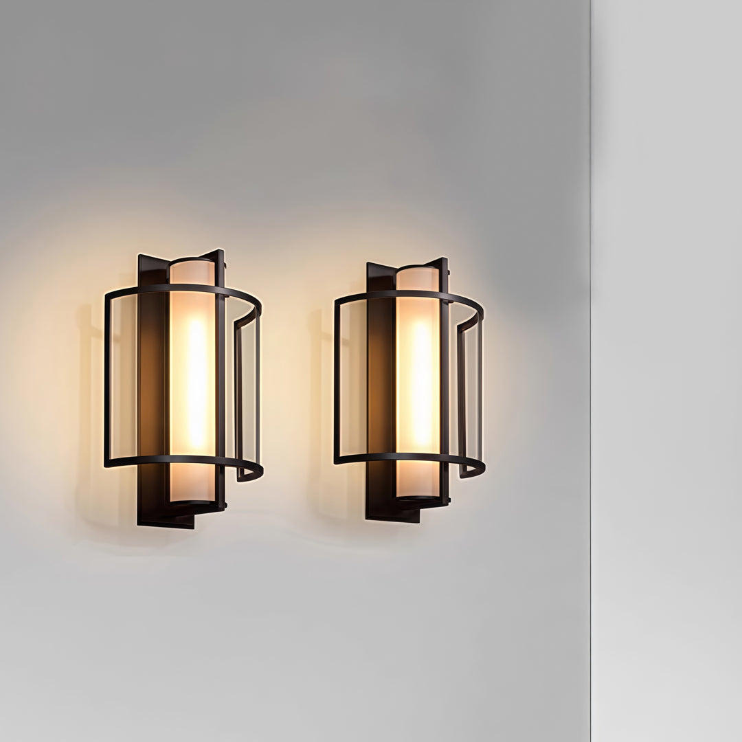 Pair of stylish outdoor wall mounted lighting fixtures displayed on neutral wall with warm diffused glow.