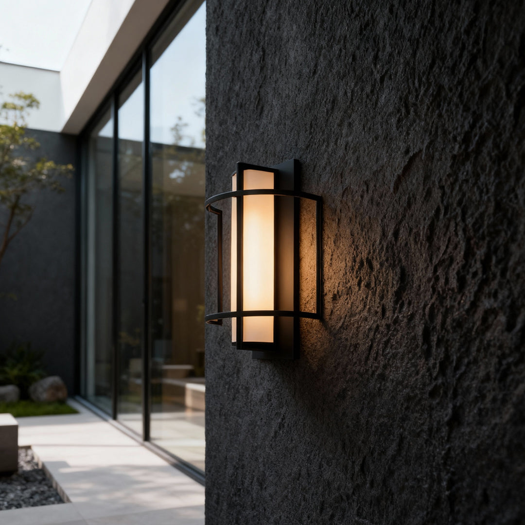 Dark textured exterior wall enhanced with warm outdoor wall mounted lighting creating inviting atmosphere.