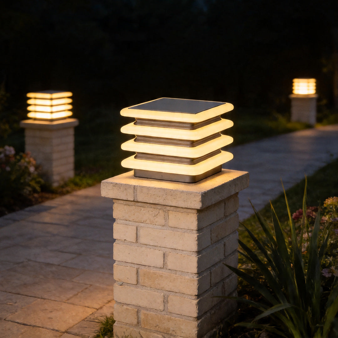 Outdoor wall pillar lights mounted on brick gate post illuminating modern garden pathway at night.
