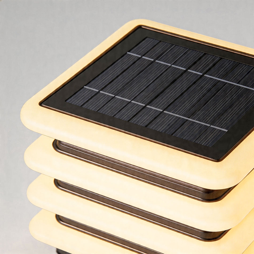 Close-up of outdoor wall pillar lights featuring integrated solar panel and layered LED structure.