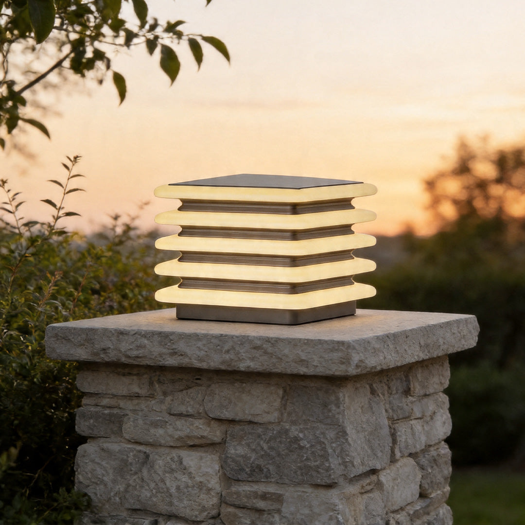 Outdoor wall pillar lights installed on stone column with warm layered LED glow at sunset.