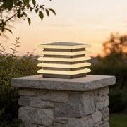 Outdoor wall pillar lights installed on stone column with warm layered LED glow at sunset.