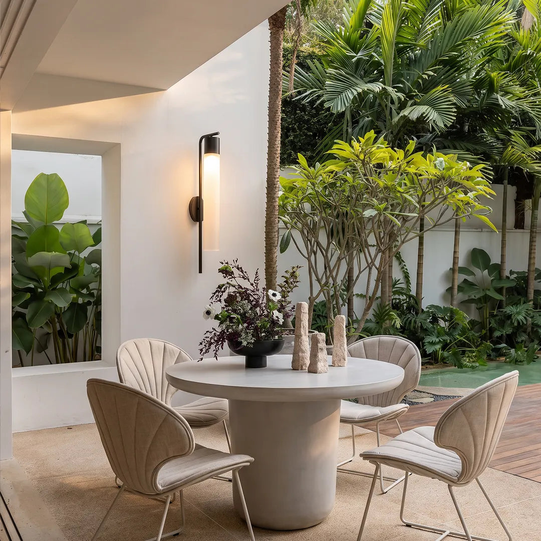 Outdoor wall sconce with warm glow beside covered patio dining area