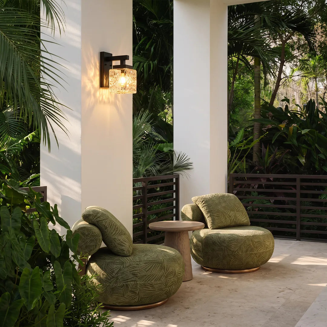 Outdoor wall sconce with warm glow beside garden patio and lounge seating