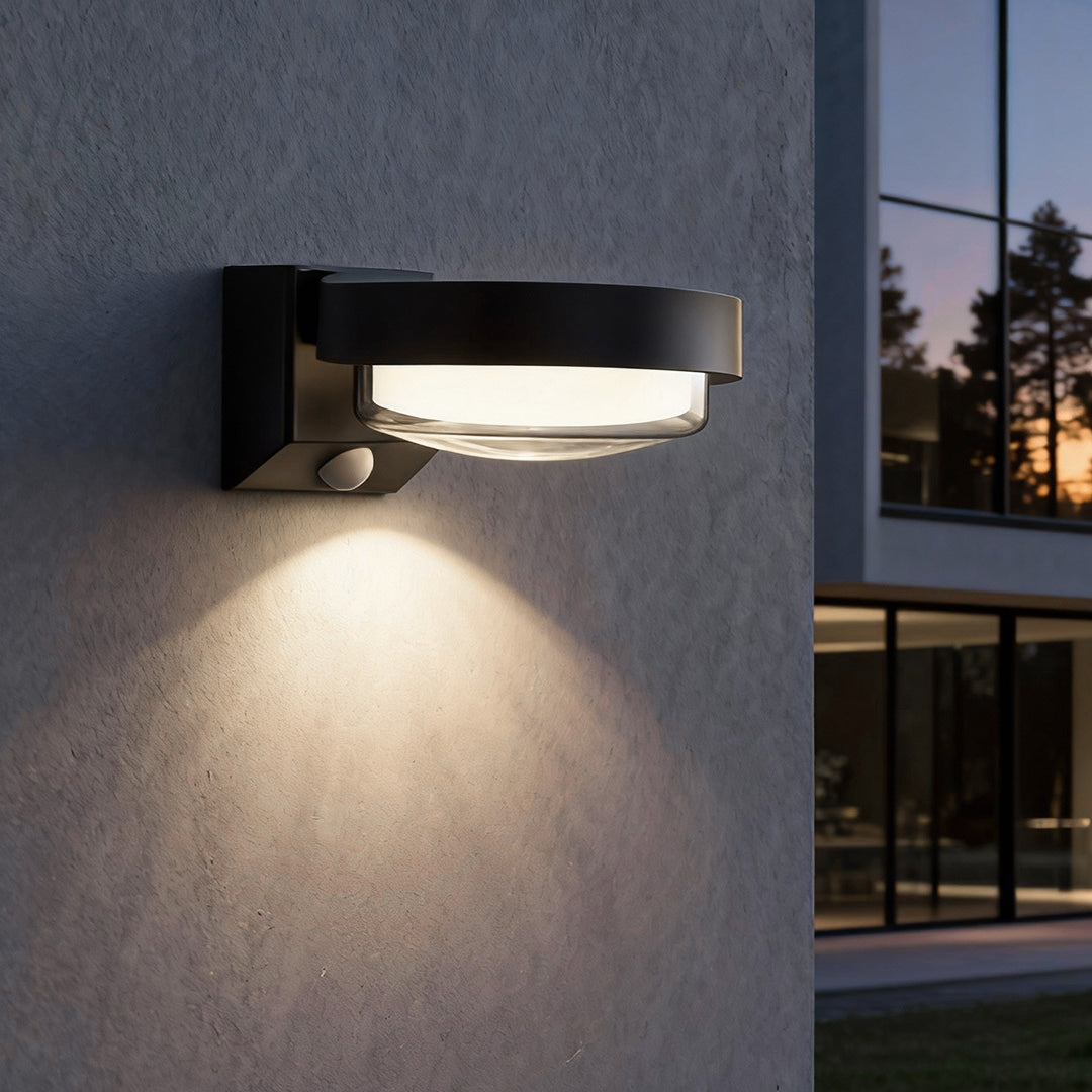 Modern outdoor wall sconce casting warm downward light against textured exterior wall.