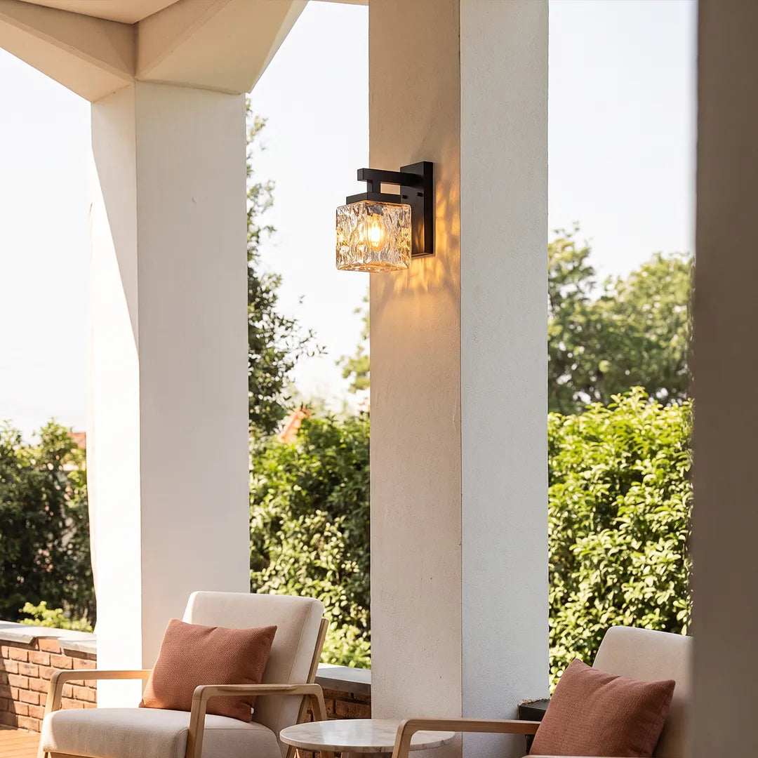Outdoor wall sconce with black frame and textured glass on porch column