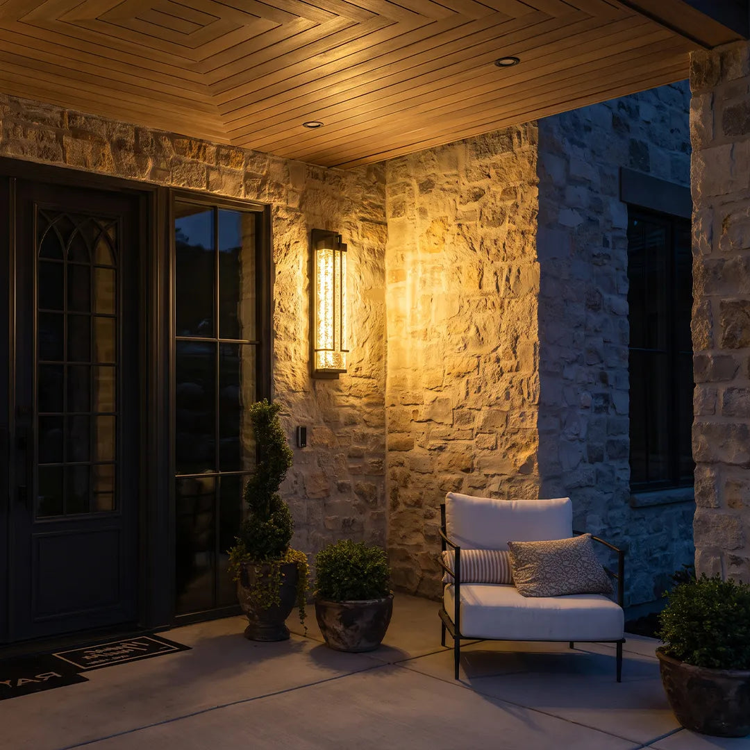 Outdoor wall sconce with textured glass illuminating covered stone porch