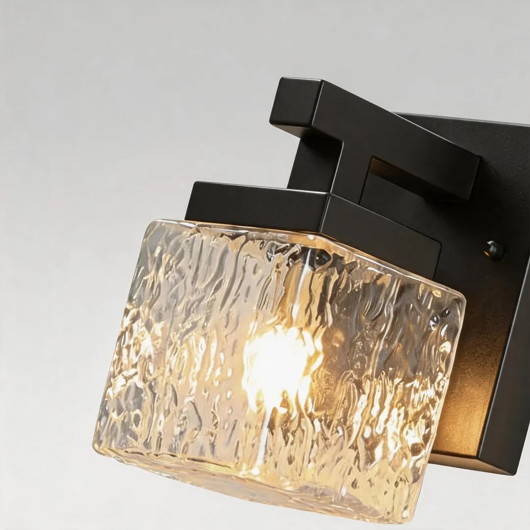 Outdoor wall sconce with textured clear glass shade and black metal frame detail