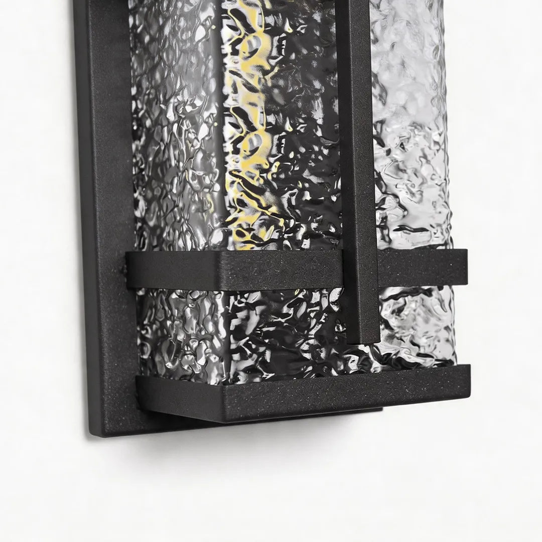 Outdoor wall sconce with textured glass shade and black metal frame detail