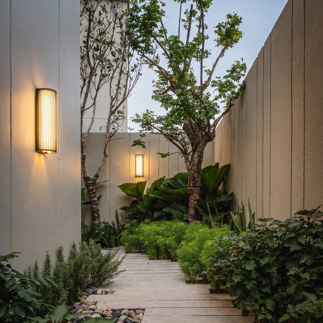 Outdoor wall sconces illuminating landscaped garden walkway with warm light