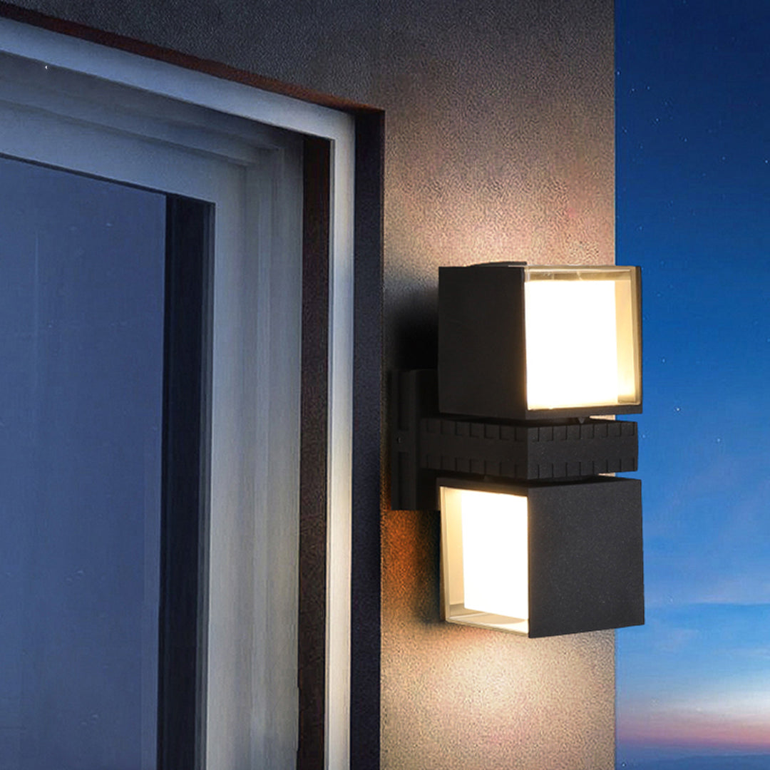 Close-up nighttime view of outdoor wall up lighting fixture mounted beside a doorway providing warm focused light.