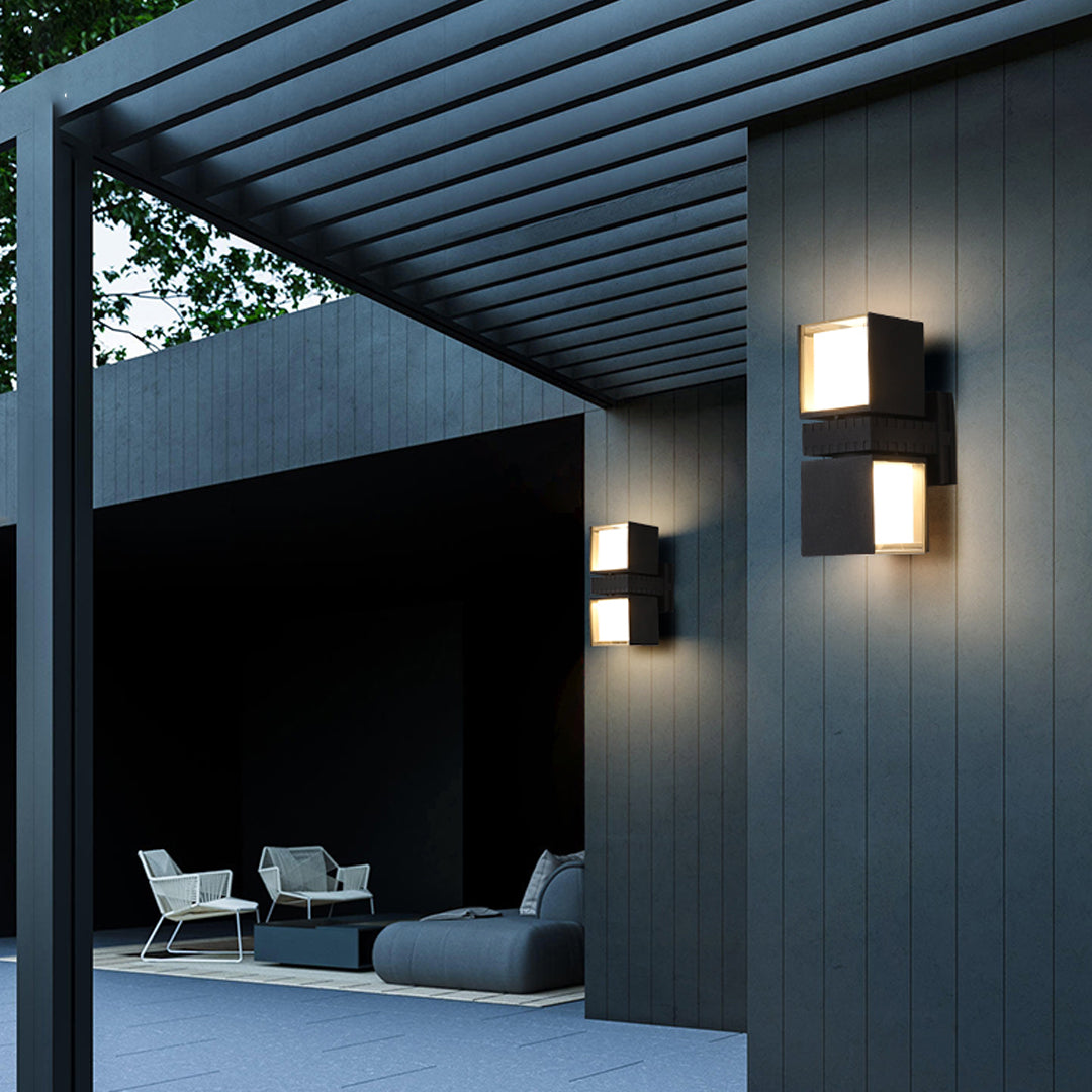Outdoor entertainment area illuminated by modern outdoor wall up lighting fixtures mounted on dark exterior walls.