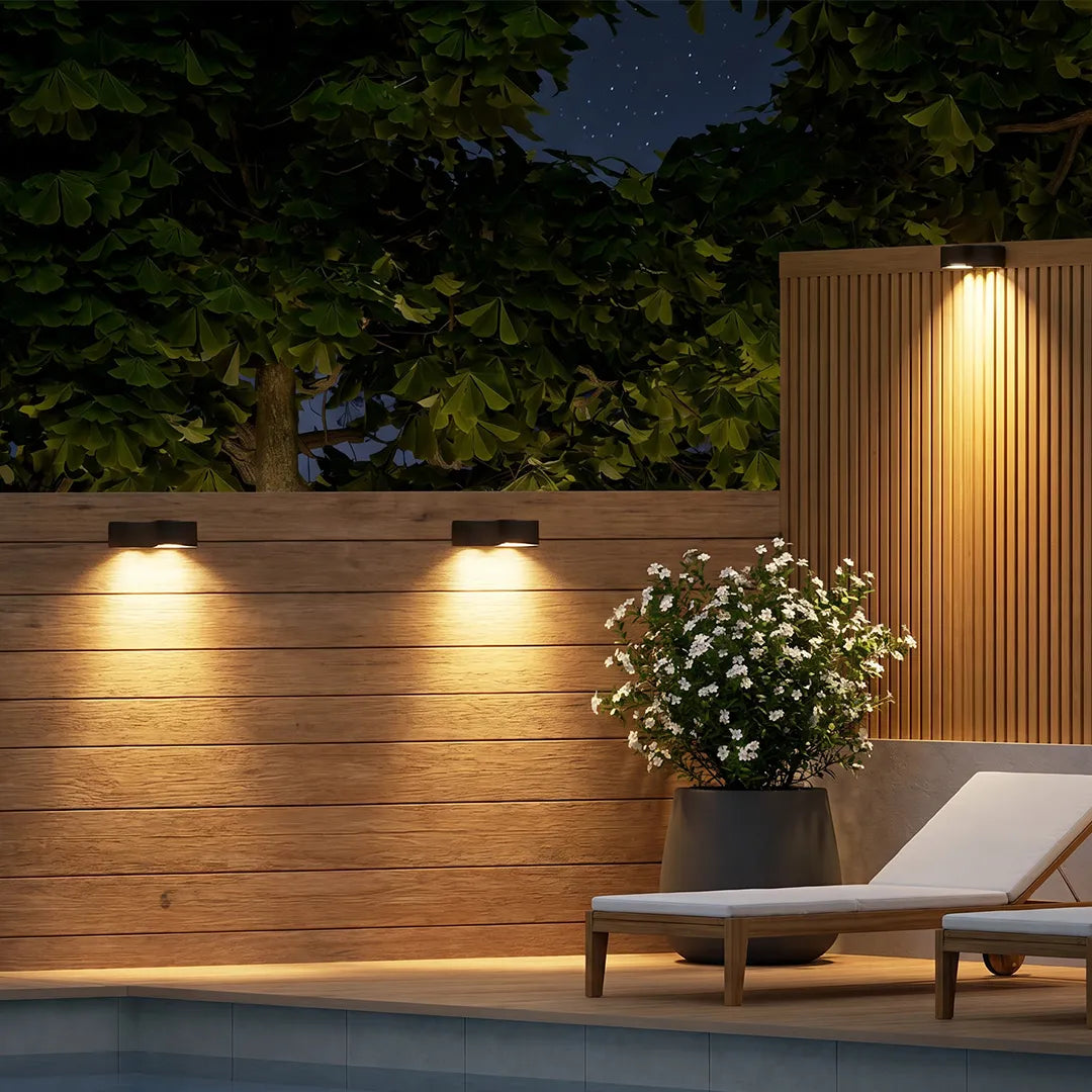 Outdoor wall wash lighting mounted on a wood fence to create warm accent illumination above a patio lounge area.