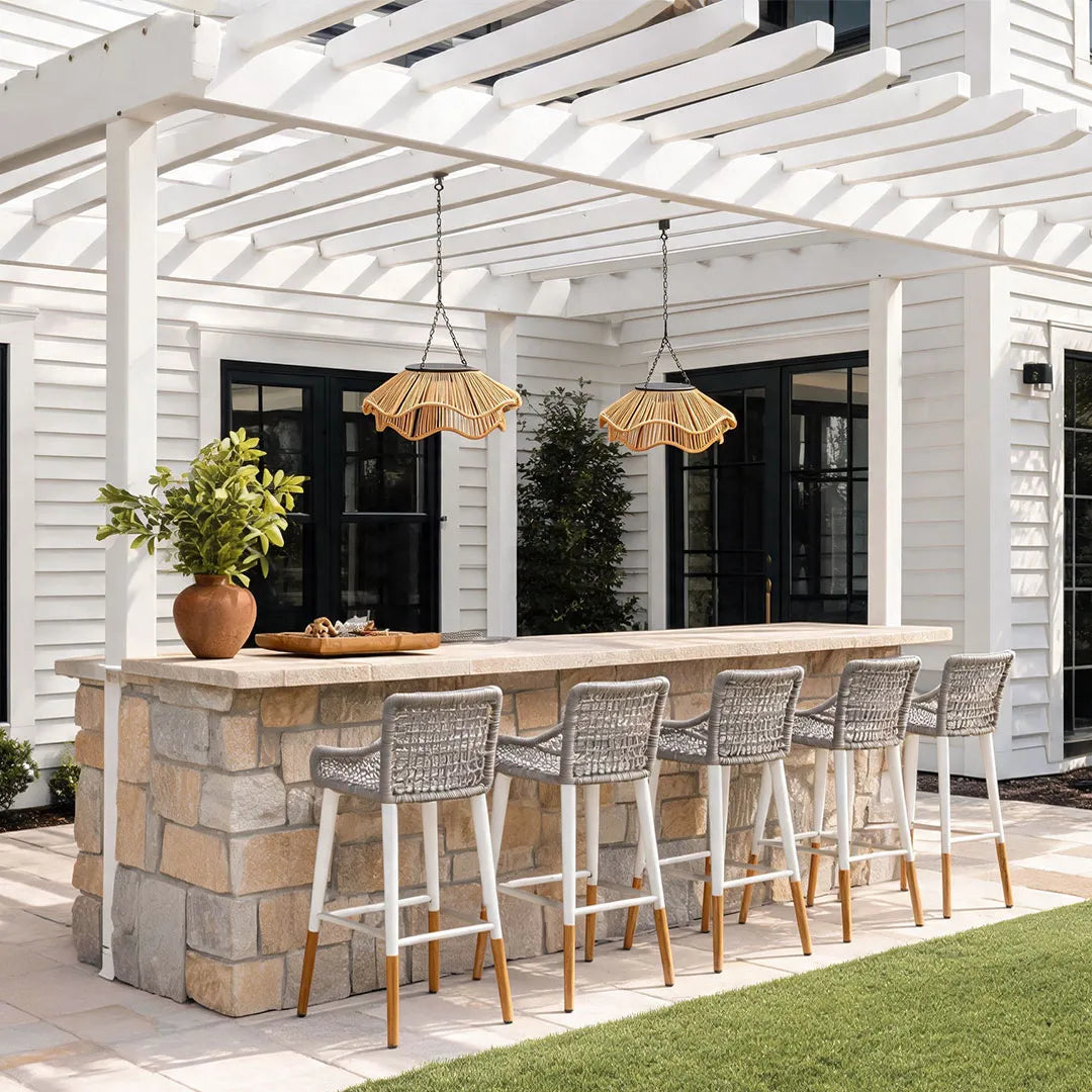 Outdoor woven pendant light installed above a patio bar beneath a white pergola.