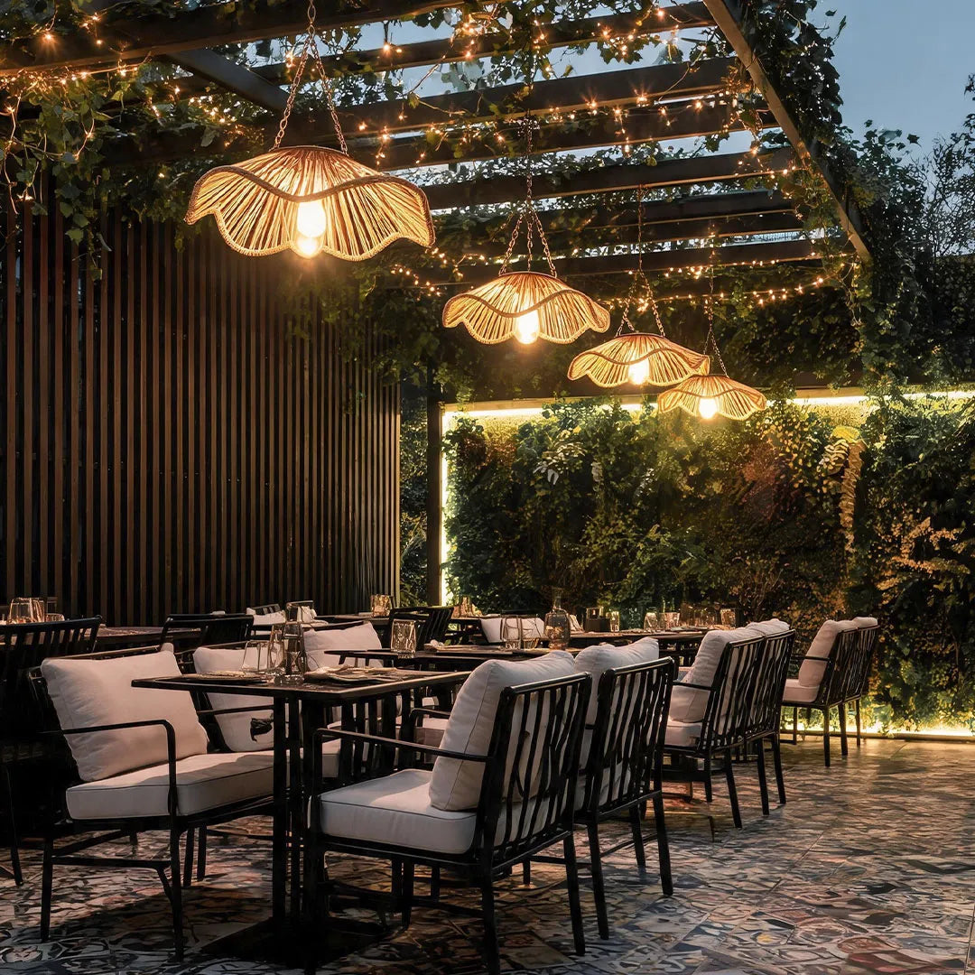 Outdoor woven pendant light creating warm ambient lighting above an outdoor restaurant terrace.