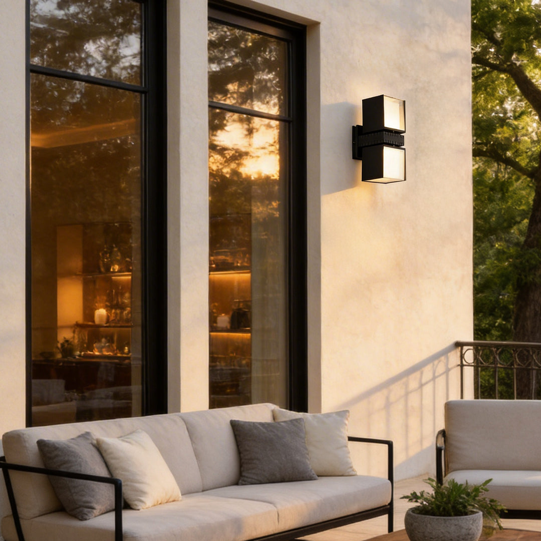 Outside up down wall lights illuminating a contemporary outdoor sofa and garden.