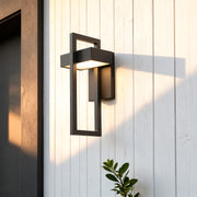 Oval bulkhead wall light installed beside a stone exterior door, emitting warm ambient lighting.