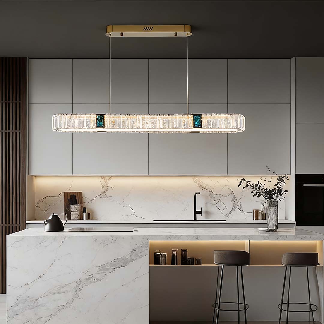 Oval crystal chandelier with a gold frame, illuminating a modern kitchen island.