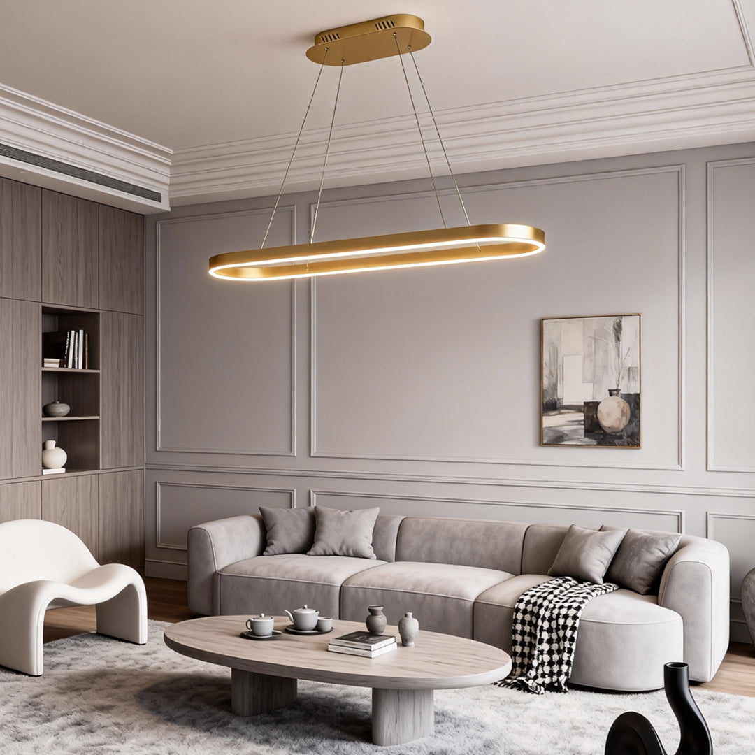 Gold oval LED pendant light suspended in a classic living room with decorative wall molding.