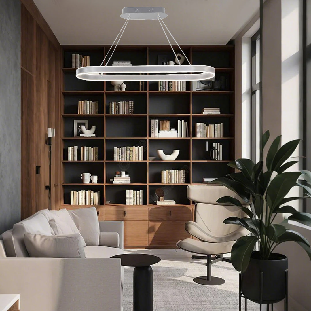 Linear oval LED pendant light illuminating a home office with built-in bookshelves.