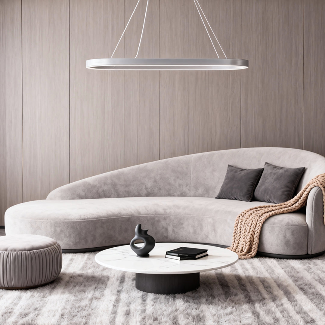 Oval LED pendant light hanging above a curved sofa in a minimalist living room.