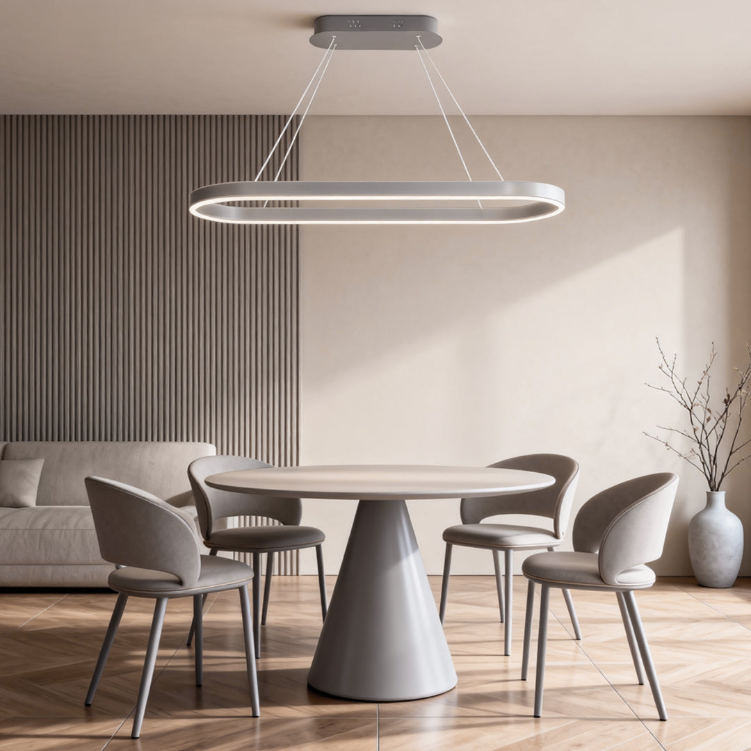 Modern oval LED pendant light installed above a minimalist dining table with soft ambient lighting.