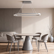 Modern oval LED pendant light installed above a minimalist dining table with soft ambient lighting.