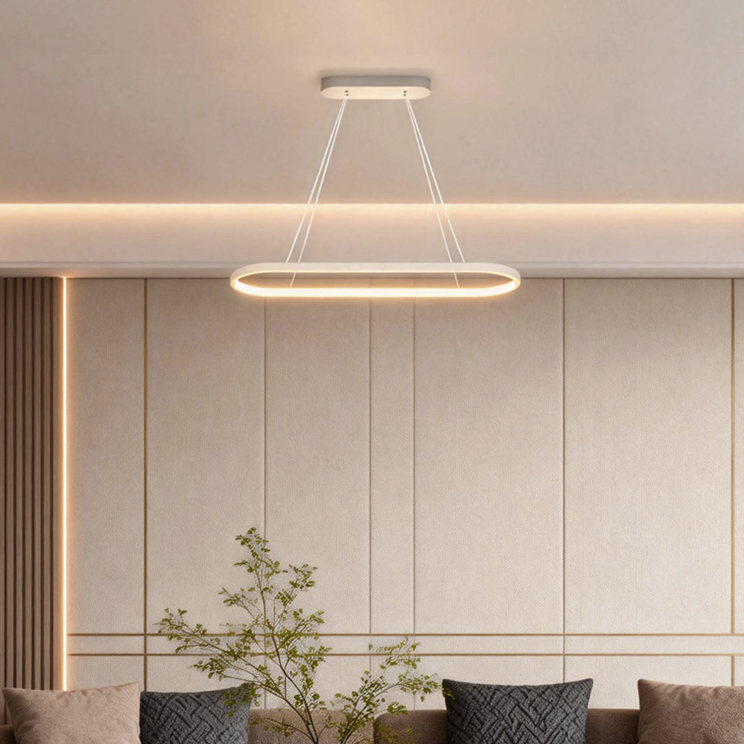 Oval linear pendant light hanging above living room seating area.