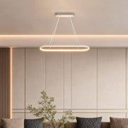Oval linear pendant light hanging above living room seating area.