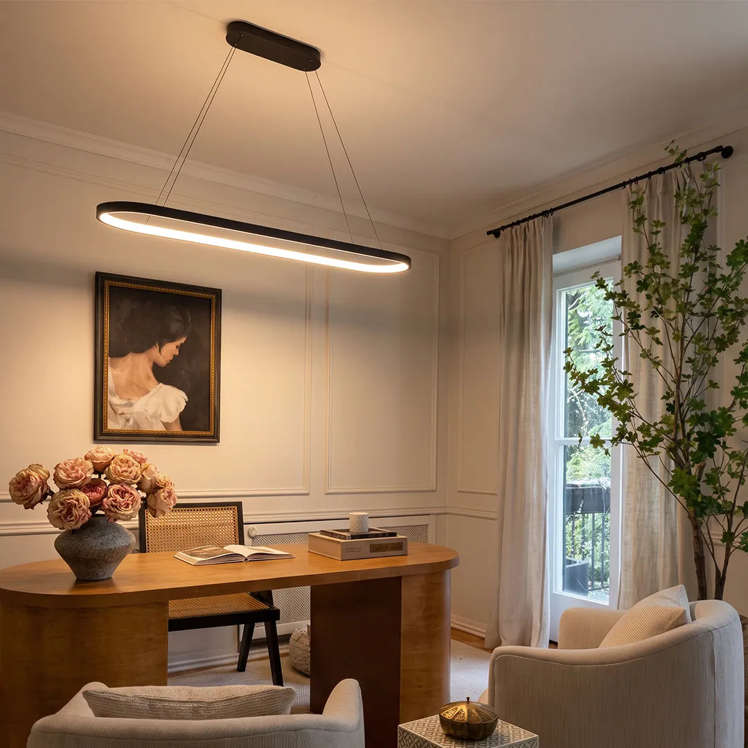 Oval pendant light suspended above a wooden dining table in a warm contemporary room with soft ambient lighting.